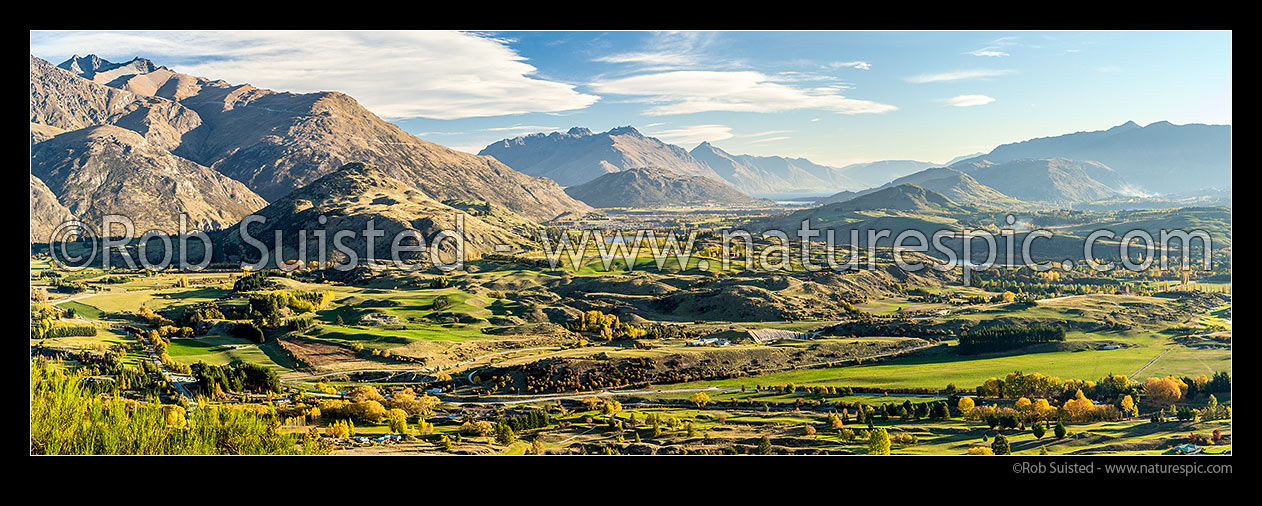 Image of Queenstown's Kawarau River basin panorama, seen from above Arrowtown. Queenstown and Lake Wakatipu distant, The Remarkables left, Walter Peak distand centre. Autumn colours, Arrowtown, Queenstown Lakes District, Otago Region, New Zealand (NZ) stock photo image