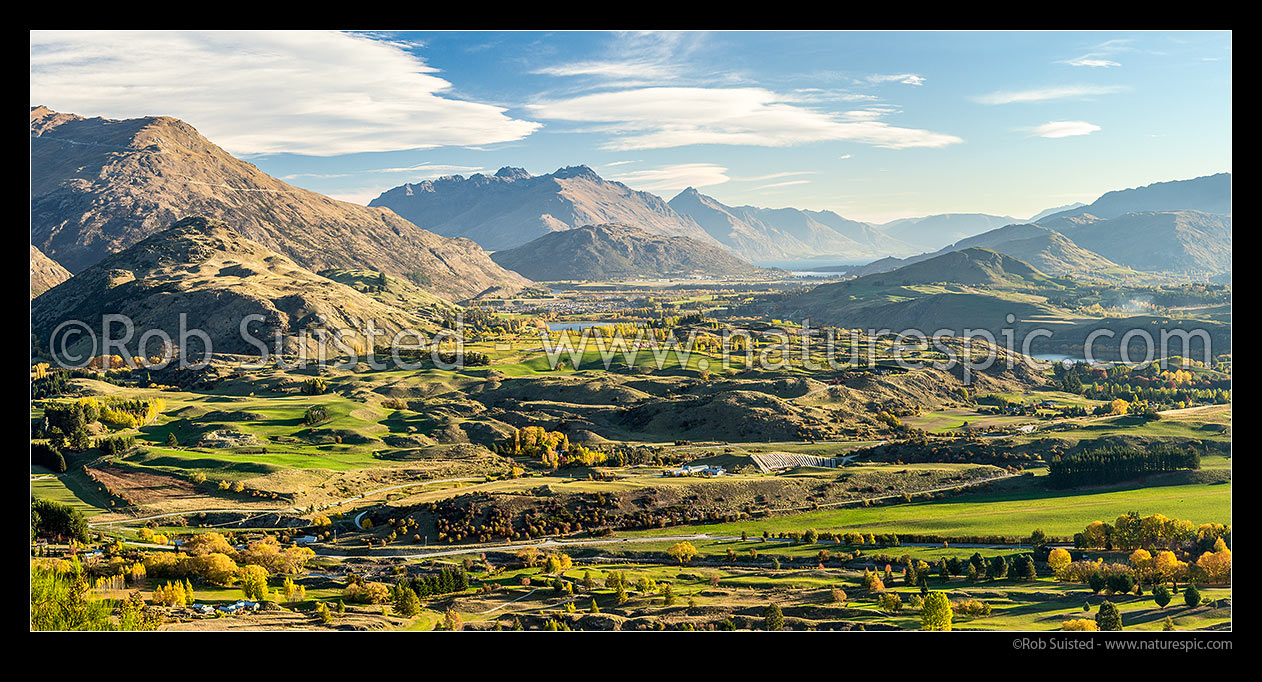 Image of Queenstown's Kawarau River basin panorama, seen from above Arrowtown. Queenstown and Lake Wakatipu distant, The Remarkables left, Walter Peak distand centre. Autumn colours, Arrowtown, Queenstown Lakes District, Otago Region, New Zealand (NZ) stock photo image