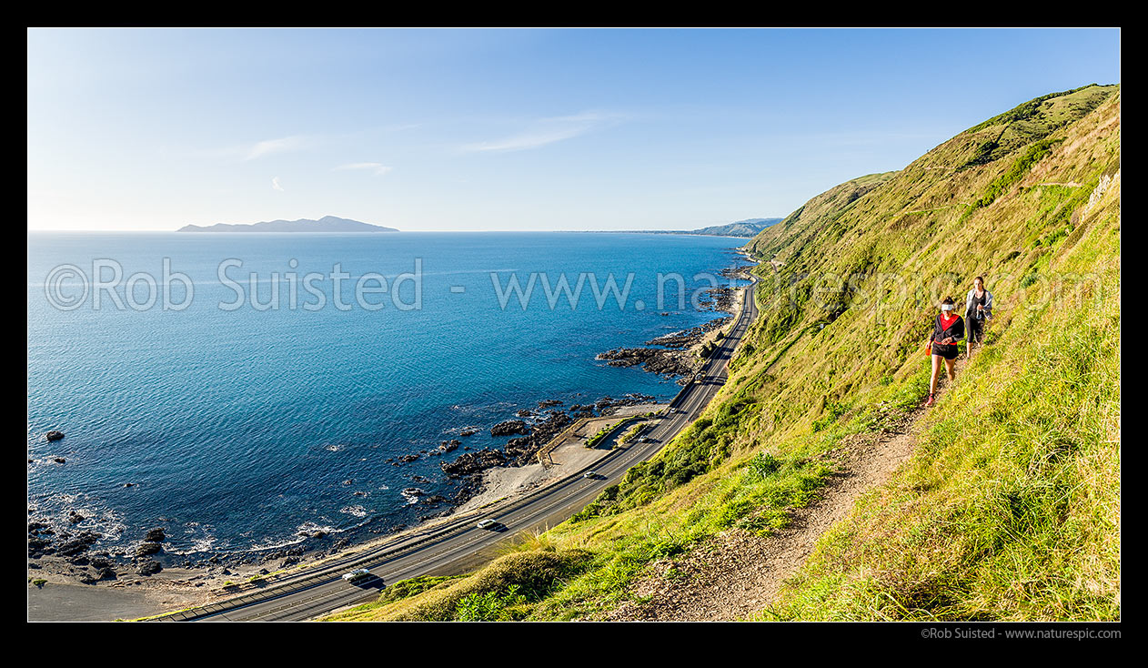 Image of Escarpment Track with walkers high above coastline and Kapiti Island. A walking track linking Paekakariki to Pukerua Bay. Panorama, Pukerua Bay, Kapiti Coast District, Wellington Region, New Zealand (NZ) stock photo image