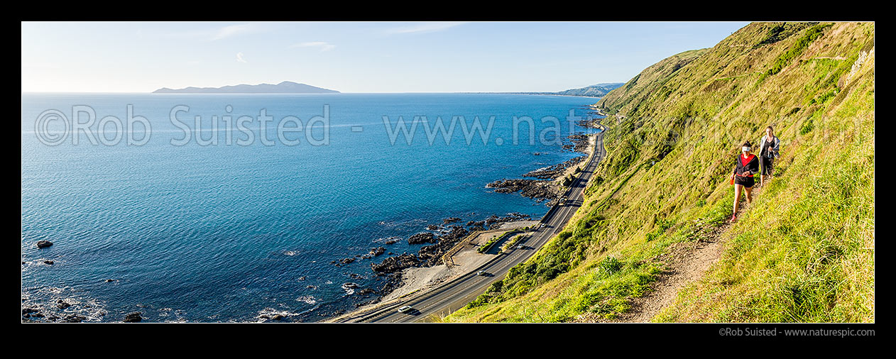 Image of Escarpment Track with walkers high above coastline and Kapiti Island. A walking track linking Paekakariki to Pukerua Bay. Panorama, Pukerua Bay, Kapiti Coast District, Wellington Region, New Zealand (NZ) stock photo image