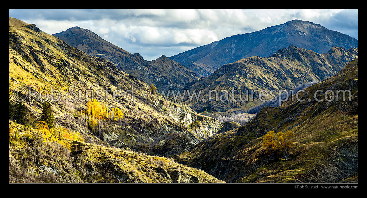 Image of Shotover River valley near historic Skippers township. Sainsbury Huts centre and The Branches Road visible at left. Silverhorn Peak (1749m) above. Autumn panorama, Skippers, Queenstown Lakes District, Otago Region, New Zealand (NZ) stock photo image