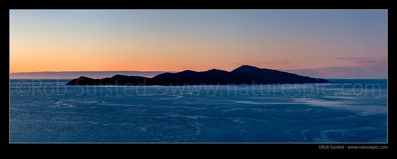 Image of Kapiti Island at twilight, silhouetted against sunset. Mt Taranaki just visible on left end. Kapiti Island Nature Reserve. Panorama, Paekakariki, Kapiti Coast District, Wellington Region, New Zealand (NZ) stock photo image