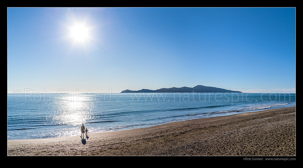 Image of Kapiti Island offshore of Paekakariki Beach on a sunny day. Mother and child enjoying the beach by themselves. Panorama, Paekakariki, Kapiti Coast District, Wellington Region, New Zealand (NZ) stock photo image