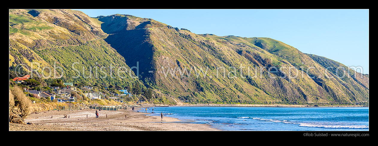 Image of Paekakariki Beach panorama. People fishing and walking on beach, with Paekakariki Hill Road above the small coastal community, Paekakariki, Kapiti Coast District, Wellington Region, New Zealand (NZ) stock photo image