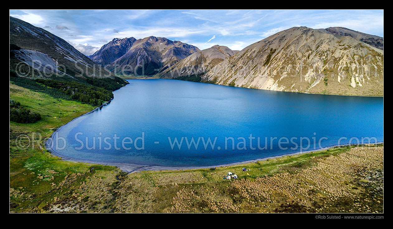 Image of Lake Tennyson Scenic Reserve near the head of the Clarence River, inland Marlborough, with people camping on the shoreline. Crimea Range beyond. Aerial panorama, Molesworth Station, Hurunui District, Canterbury Region, New Zealand (NZ) stock photo image