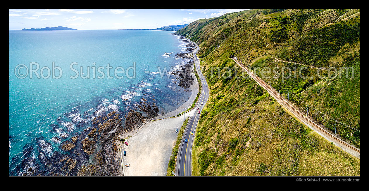 Image of State Highway One (1) along the Pukerua Bay Paekakariki Kapiti Coast, with Main Trunk Railway Line and Escarpment Track above. Kapiti Island left. Aerial panorama, Pukerua Bay, Porirua City District, Wellington Region, New Zealand (NZ) stock photo image