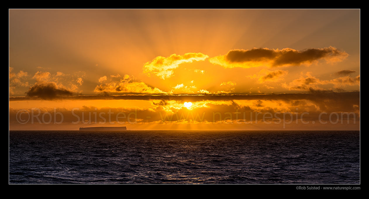 Image of Sunset and tabular iceberg. Sun behind clouds creating crepuscular sun rays over the Southern Ocean. Panorama, Southern Ocean, Antarctica Region, Antarctica stock photo image