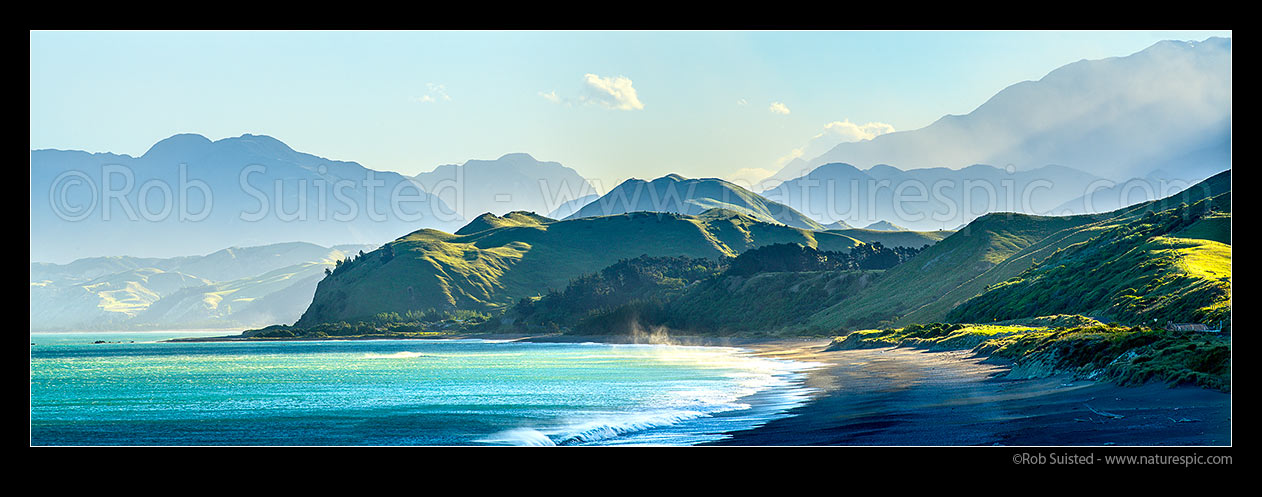 Image of Kaikoura Coastline at Kekerengu. Late afternoon sun on hills and Seaward Kaikoura Ranges, beach and coastal farmland. Wind gust lifting sea spray. Panorama, Kekerengu, Kaikoura District, Canterbury Region, New Zealand (NZ) stock photo image