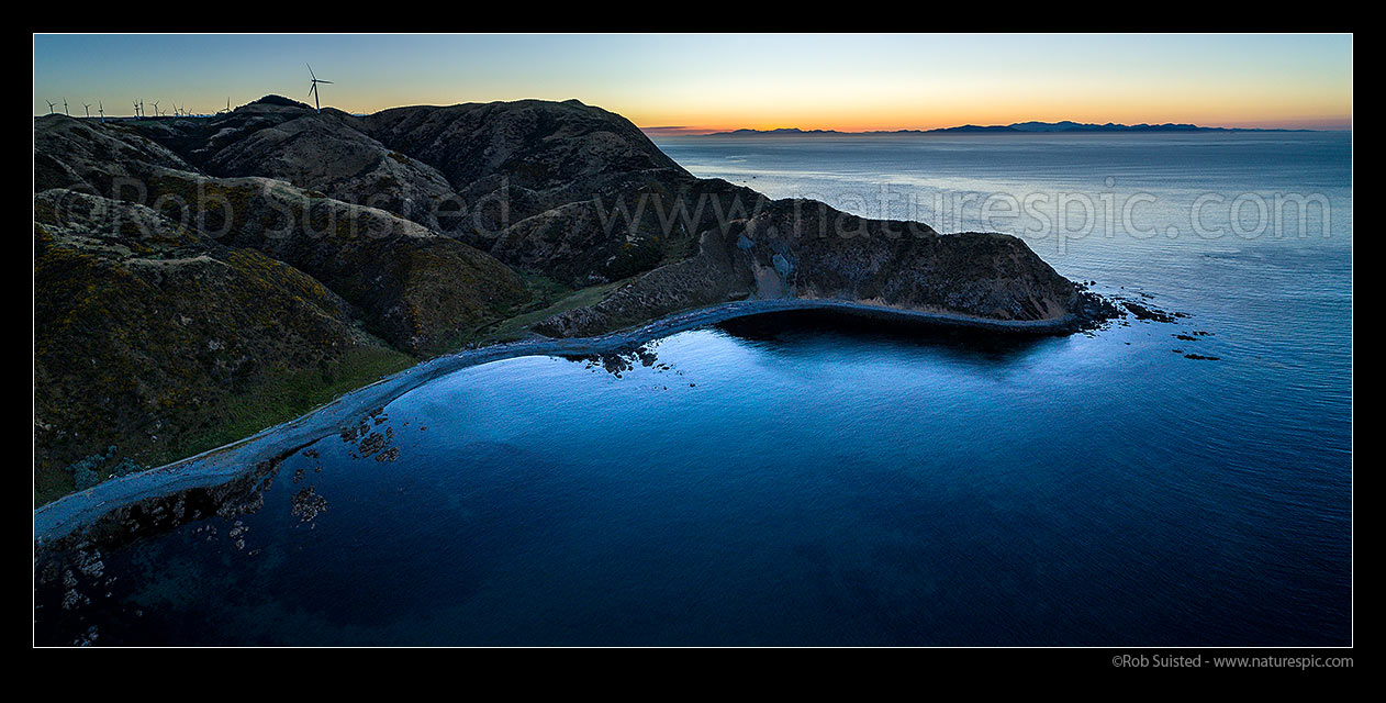 Image of Makara Beach sunset. Wharehou Bay below and South Island beyond over Cook Strait. West Wind Farm turbines above left. Aerial panorama, Makara Beach, Wellington City District, Wellington Region, New Zealand (NZ) stock photo image