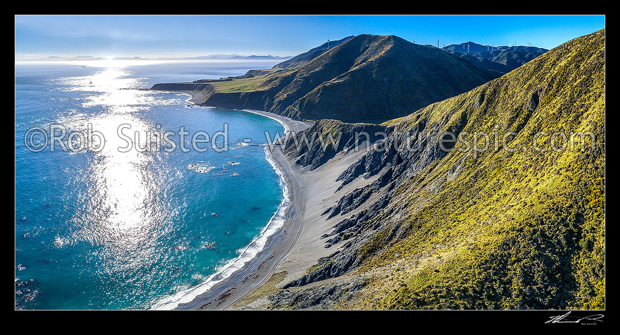 Image of Wellington South Coast. Long Bay beach below, Tongue Point and Karori Rock light left, with South Island beyond over Cook Strait. West Wind turbine farm at right. Aerial panorama, Wellington South Coast, Wellington City District, Wellington Region, New Zealand (NZ) stock photo image