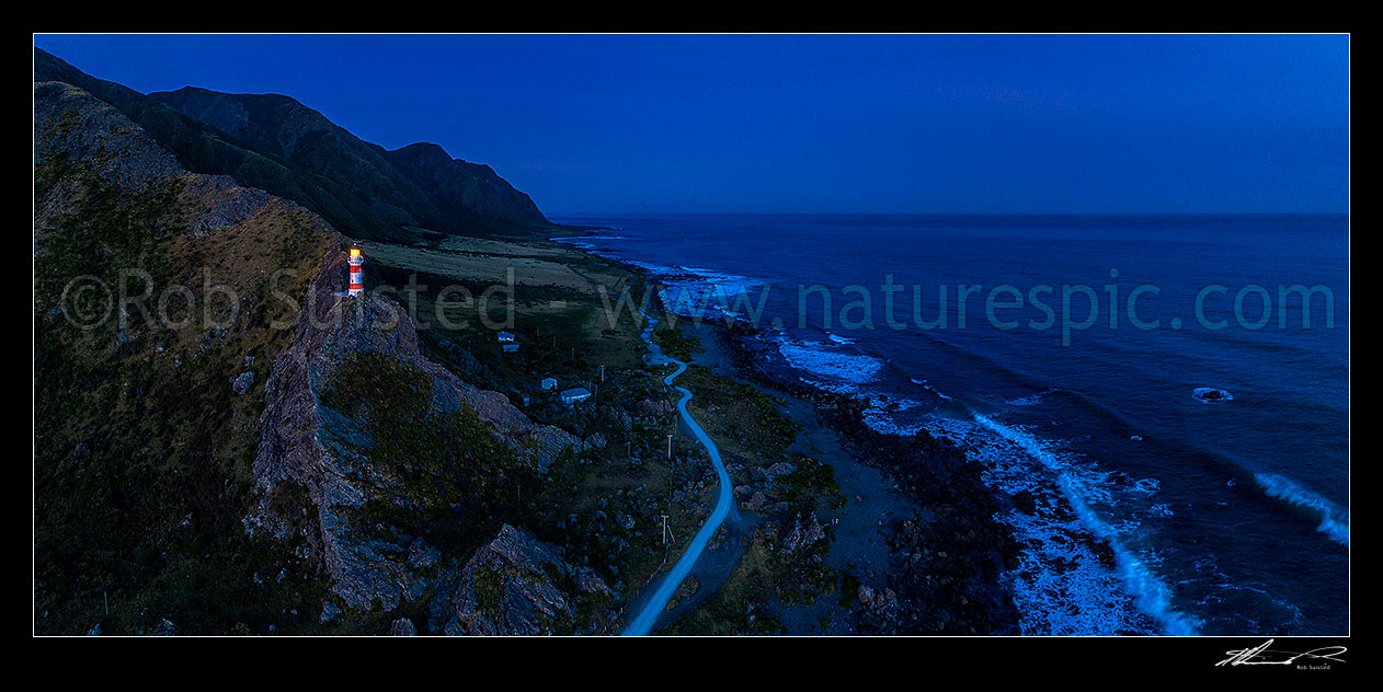 Image of Cape Palliser, southern most point of the North Island (Matakitakiakupe). Cape Palliser Lighthouse shining in darkness with Aoraki Ranges (Haurangi Forest Park) beyond. Aerial panorama, Cape Palliser, South Wairarapa District, Wellington Region, New Zealand (NZ) stock photo image