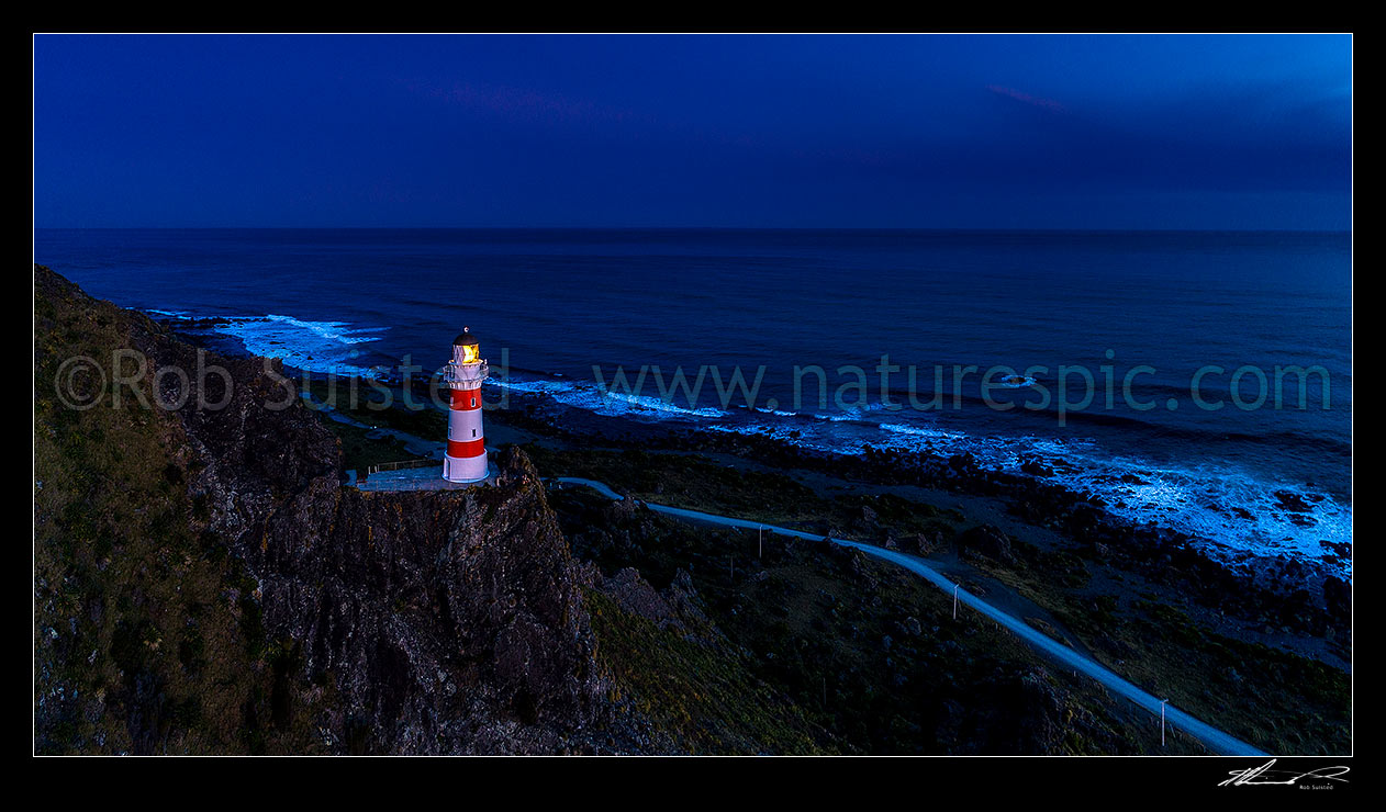 Image of Cape Palliser Lighthouse shining out from the southern most tip of the North Island (Matakitakiakupe). Aerial panorama after dark, Cape Palliser, South Wairarapa District, Wellington Region, New Zealand (NZ) stock photo image