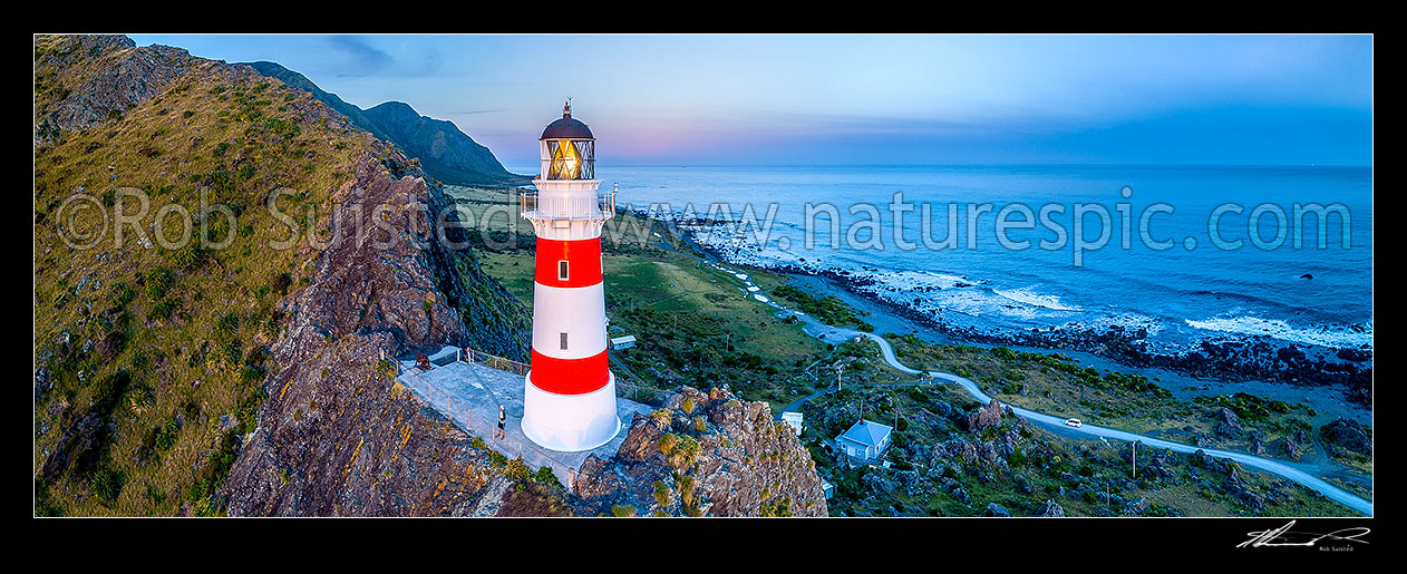 Image of Cape Palliser lighthouse on the southern most point of the North Island (Matakitakiakupe). Aerial panorama at dusk with Aoraki Ranges (Haurangi Forest Park) beyond, Cape Palliser, South Wairarapa District, Wellington Region, New Zealand (NZ) stock photo image