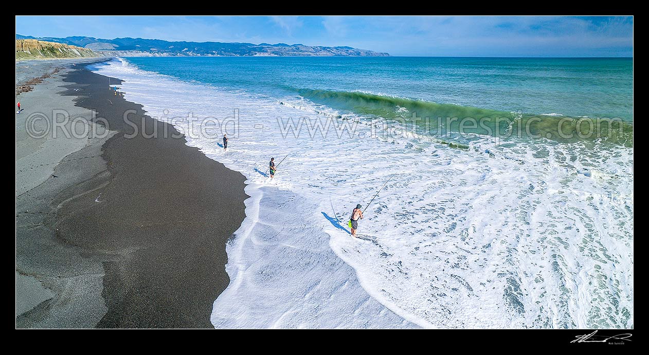 Image of Fishermen surfcasting on Whangaimoana Beach, Palliser bay. Cape Palliser beyond. Aerial panorama, Lake Ferry, South Wairarapa District, Wellington Region, New Zealand (NZ) stock photo image