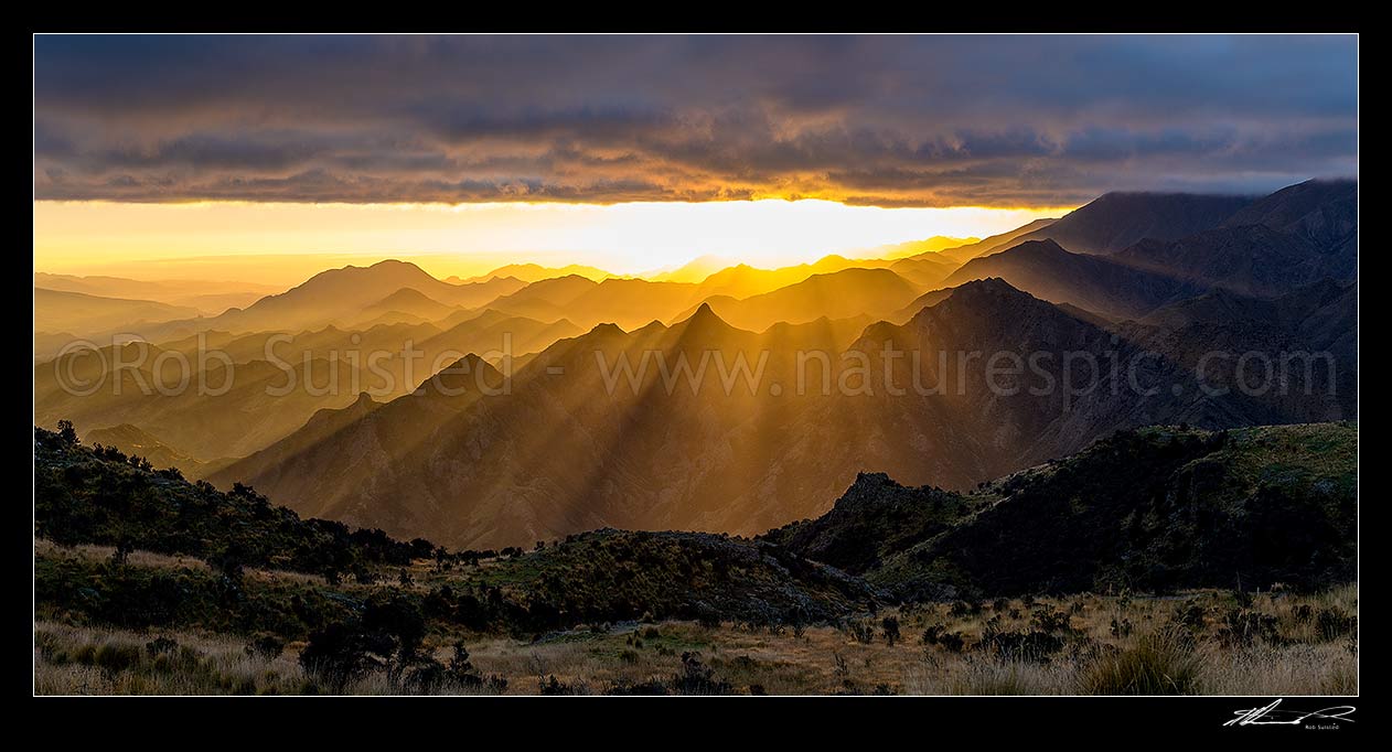 Image of Awatere Valley (left) sunrise, with crepuscular rays of sunlight lighting the Hodder River valley, Gladstone Downs and Camden Stations. Panorama, Awatere Valley, Marlborough District, Marlborough Region, New Zealand (NZ) stock photo image