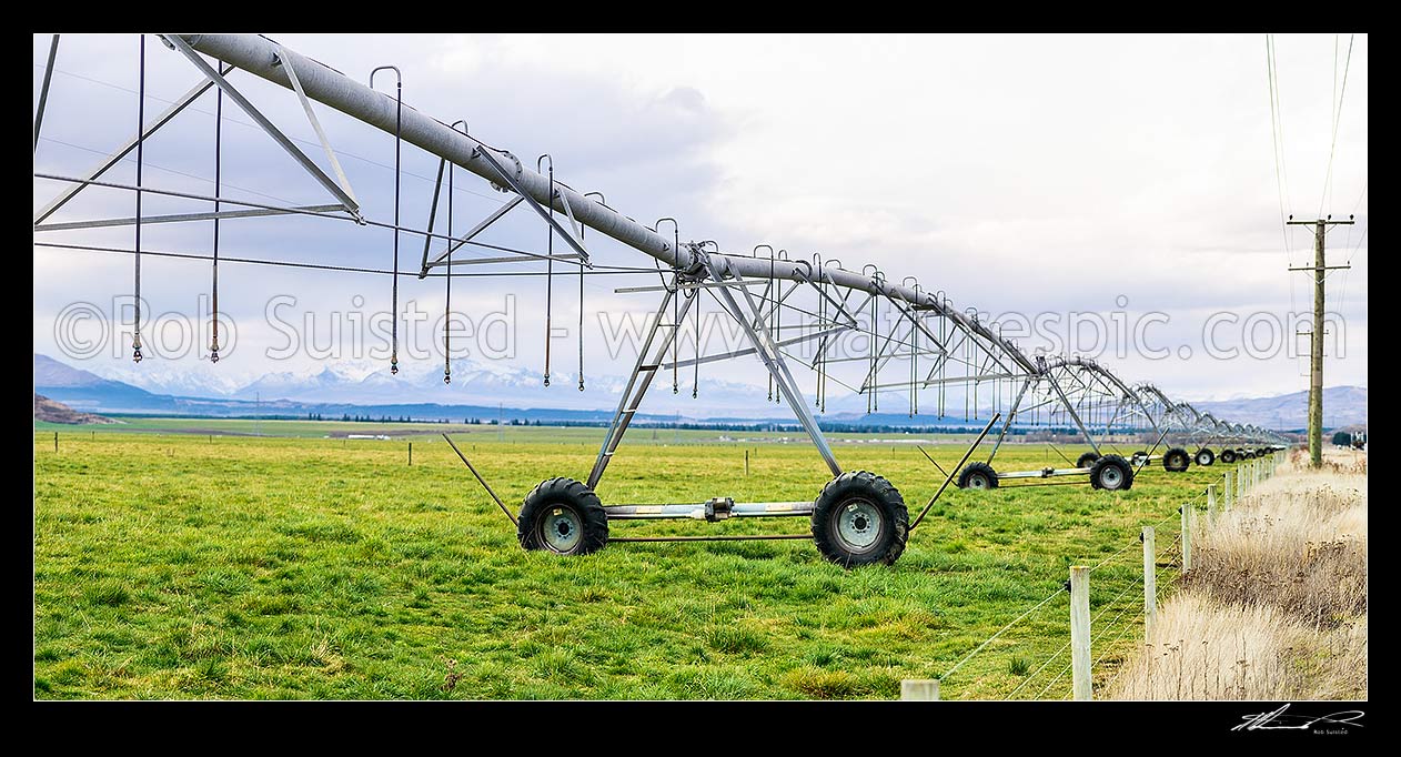 Image of Mackenzie Basin irrigation and pasture improvement for dairy farming. Pivot irrigator with southern alps behind (Burnett Mountains and Gamack Range etc). Irrigator in focus. Panorama, Twizel, MacKenzie District, Canterbury Region, New Zealand (NZ) stock photo image