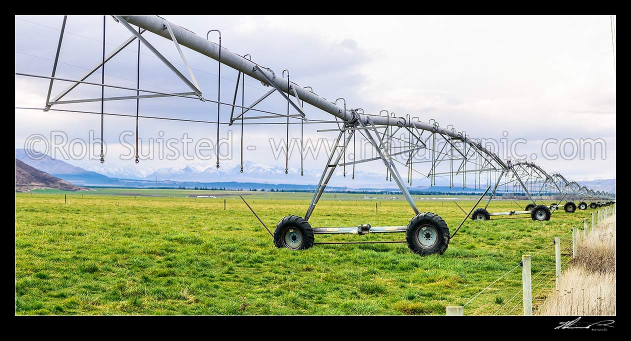 Image of Mackenzie Basin irrigation and pasture improvement for dairy farming. Pivot irrigator with southern alps behind (Burnett Mountains and Gamack Range etc). Irrigator in focus. Panorama, Twizel, MacKenzie District, Canterbury Region, New Zealand (NZ) stock photo image