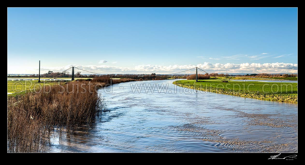 Image of Manawatu River under flood flow levels, passing under the historic Opiki toll bridge (1918). Tane flax mill chimney at left. Panorama, Opiki, Horowhenua District, Manawatu-Wanganui Region, New Zealand (NZ) stock photo image