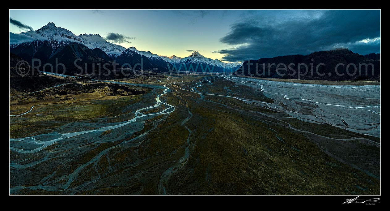 Image of Aoraki Mount Cook in the Tasman River Valley. Ben Ohau Range at left, Burnett Mountains right, with braided Tasman River flowing down valley to Lake Pukaki at dusk. Aerial panorama, Aoraki / Mount Cook National Park, MacKenzie District, Canterbury Region, New Zealand (NZ) stock photo image