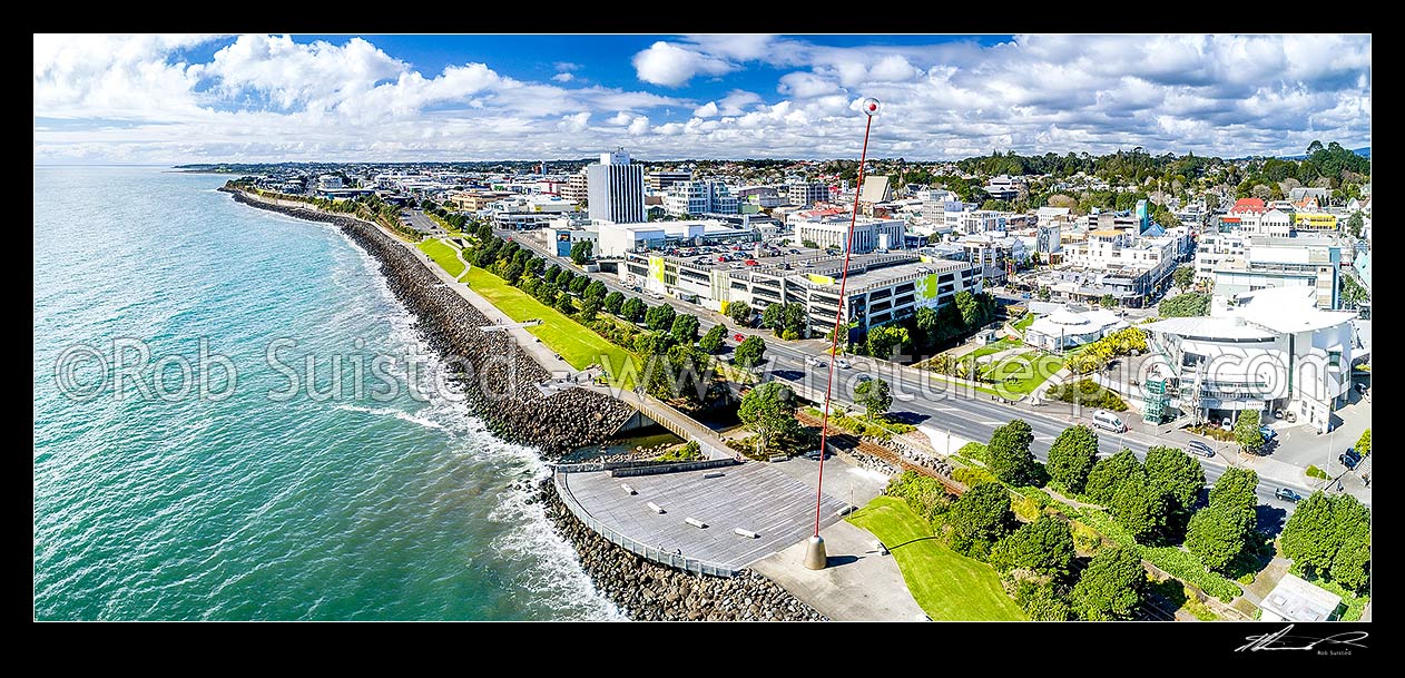 Image of New Plymouth city waterfront, with Len Lye's Wind Wand, a 48m high kinetic sculpture on the foreshore walkway. New Plymouth city CBD beyond. Aerial panorama, New Plymouth, New Plymouth District, Taranaki Region, New Zealand (NZ) stock photo image