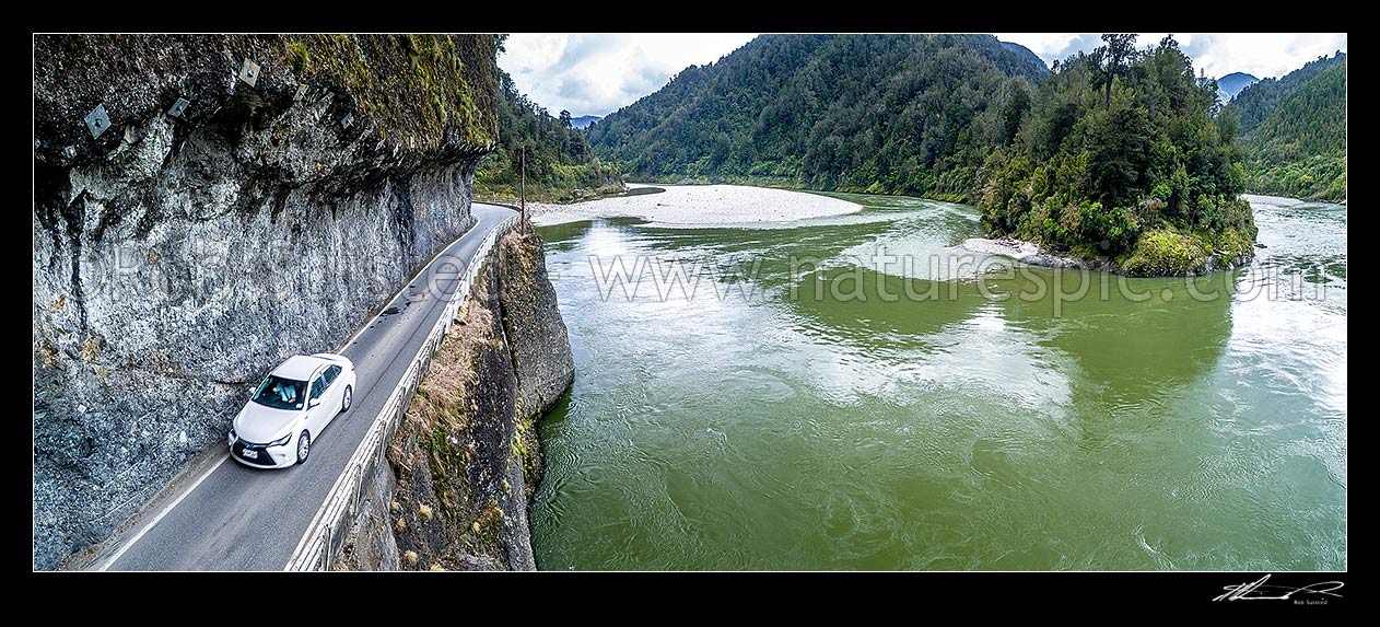 Image of Hawks Crag under cut in the Buller Gorge, beside the Buller River and Dee Point (right). State Highway 6 (SH6). Aerial panorama of car passing underneath this narrow section in Lower Buller Gorge, Westport, Buller District, West Coast Region, New Zealand (NZ) stock photo image