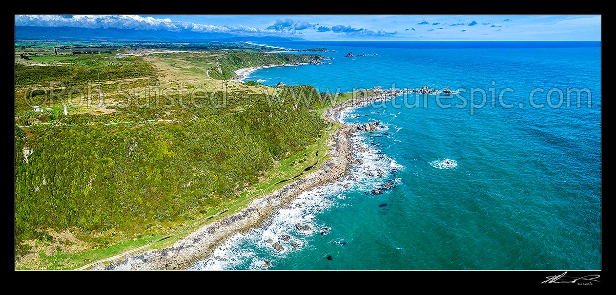 Image of Cape Foulwind. Aerial panorama looking past Cape Foulwind Lighthouse (left) and Cape Foulwind Walkway towards Tauranga Bay and Wall Island (top centre), Cape Foulwind, Buller District, West Coast Region, New Zealand (NZ) stock photo image