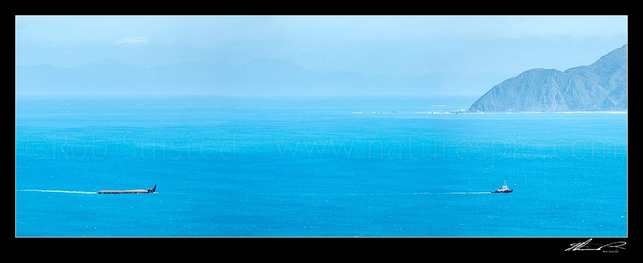 Image of Wellington Harbour entrance with tugboat towing in a barge of rocks. Sinclair Head behind. Panorama, Wellington South Coast, Wellington City District, Wellington Region, New Zealand (NZ) stock photo image