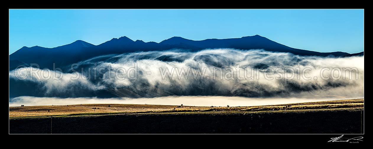 Image of MacKenzie Basin barren high country farmland traversed by powerlines and powerpoles on a moody dawn. Panorama. Abstract, Tekapo, MacKenzie District, Canterbury Region, New Zealand (NZ) stock photo image