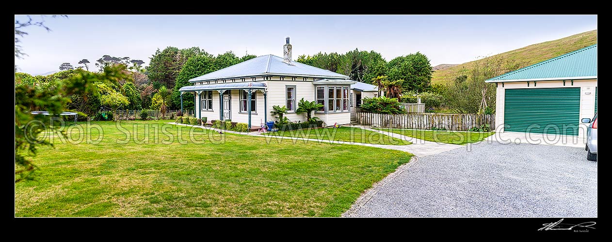 Image of Old neatly kept farmhouse, garage and lawn, with childrens toys about. Panorama, New Zealand (NZ) stock photo image