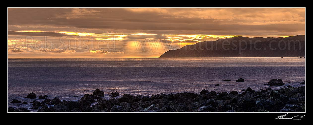 Image of Wellington South Coast and Cook Strait with spectactular light show at sunset over Sinclair Head (centre). Panorama, Turakirae Head, Hutt City District, Wellington Region, New Zealand (NZ) stock photo image