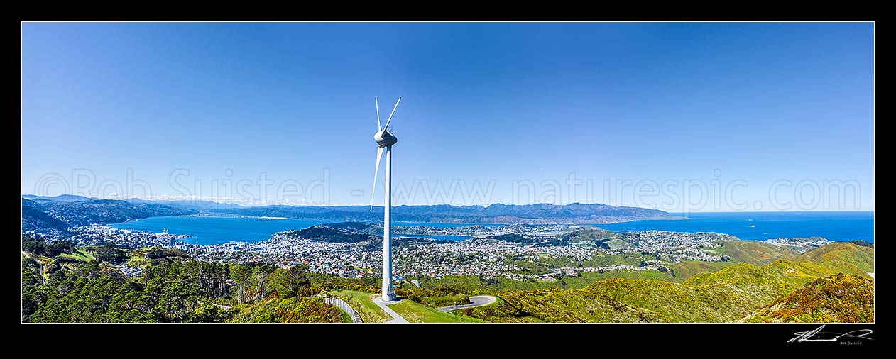 Image of Wellington's Brooklyn wind turbine above Wellington Wellington City and Harbour left, and Cape Turakirae, South coast and Cook Strait right. Aerial panorama view, Wellington, Wellington City District, Wellington Region, New Zealand (NZ) stock photo image