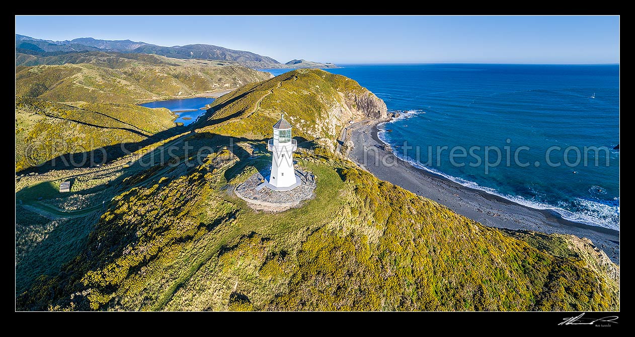 Image of Historic Pencarrow lighthouse above Wellington Harbour entrance (1855), NZ's first lighthouse, with visitors to East Harbour Regional Park. Aerial panorama south past Lake Kohungapiripiri towards Baring Head, Pencarrow Head, Hutt City District, Wellington Region, New Zealand (NZ) stock photo image