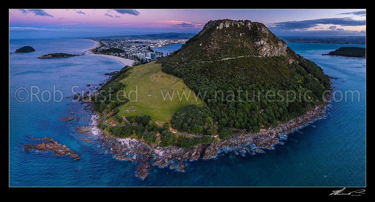 Image of Mount Maunganui, or Mauao, at the Tauranga Harbour Entrance. 231m high lava dome. Moturiki and Motuotau Islands at left. Aerial panorama at dusk, Mount Maunganui, Tauranga District, Bay of Plenty Region, New Zealand (NZ) stock photo image