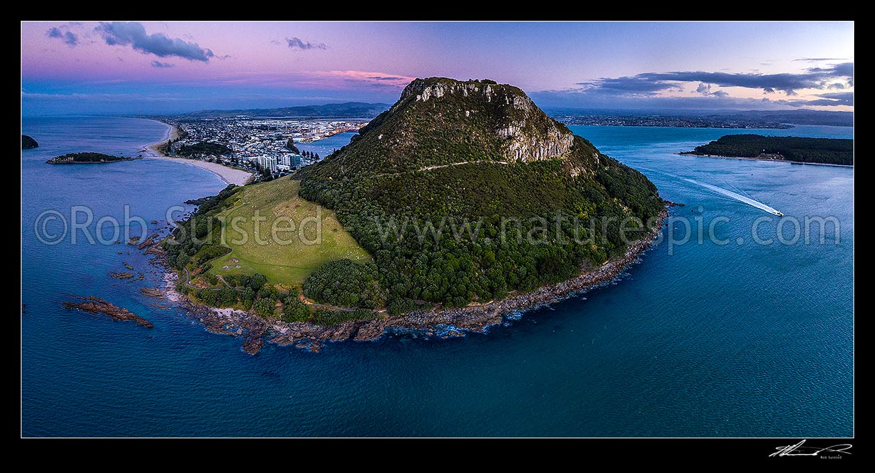 Image of Mount Maunganui, or Mauao, at the Tauranga Harbour Entrance. 231m high lava dome. Moturiki Island at left. Aerial panorama at dusk, Mount Maunganui, Tauranga District, Bay of Plenty Region, New Zealand (NZ) stock photo image