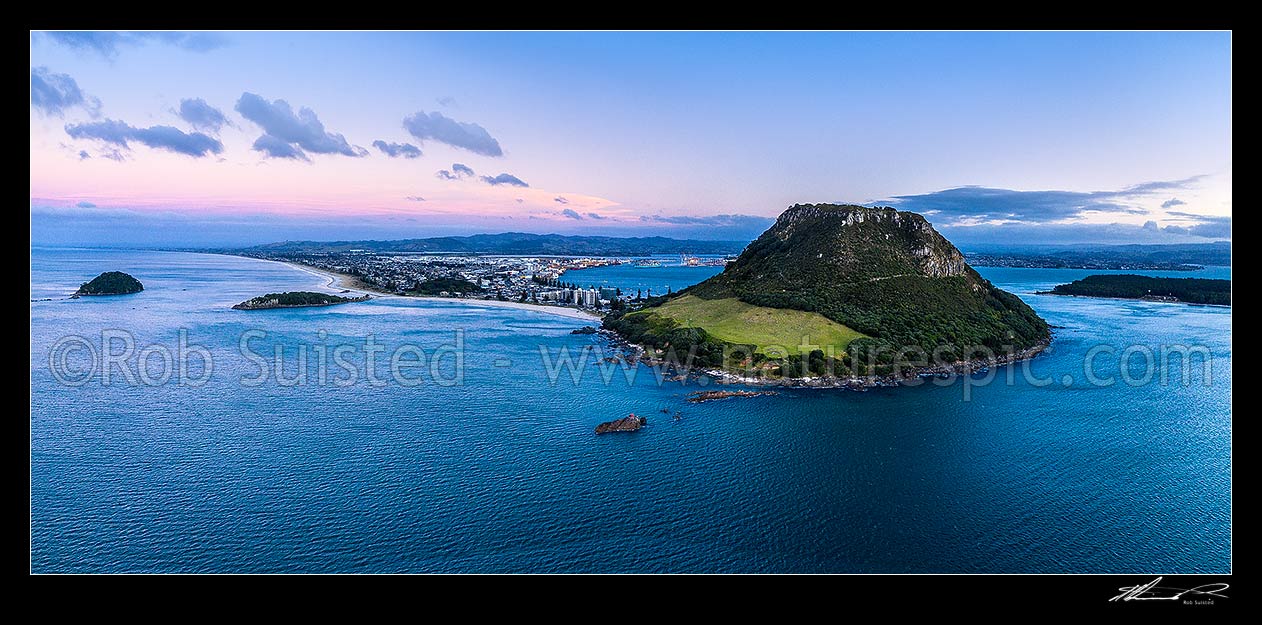 Image of Mount Maunganui, or Mauao, at the Tauranga Harbour Entrance. 231m high lava dome. Moturiki and Motuotau Islands at left. Aerial view at dusk, Mount Maunganui, Tauranga District, Bay of Plenty Region, New Zealand (NZ) stock photo image