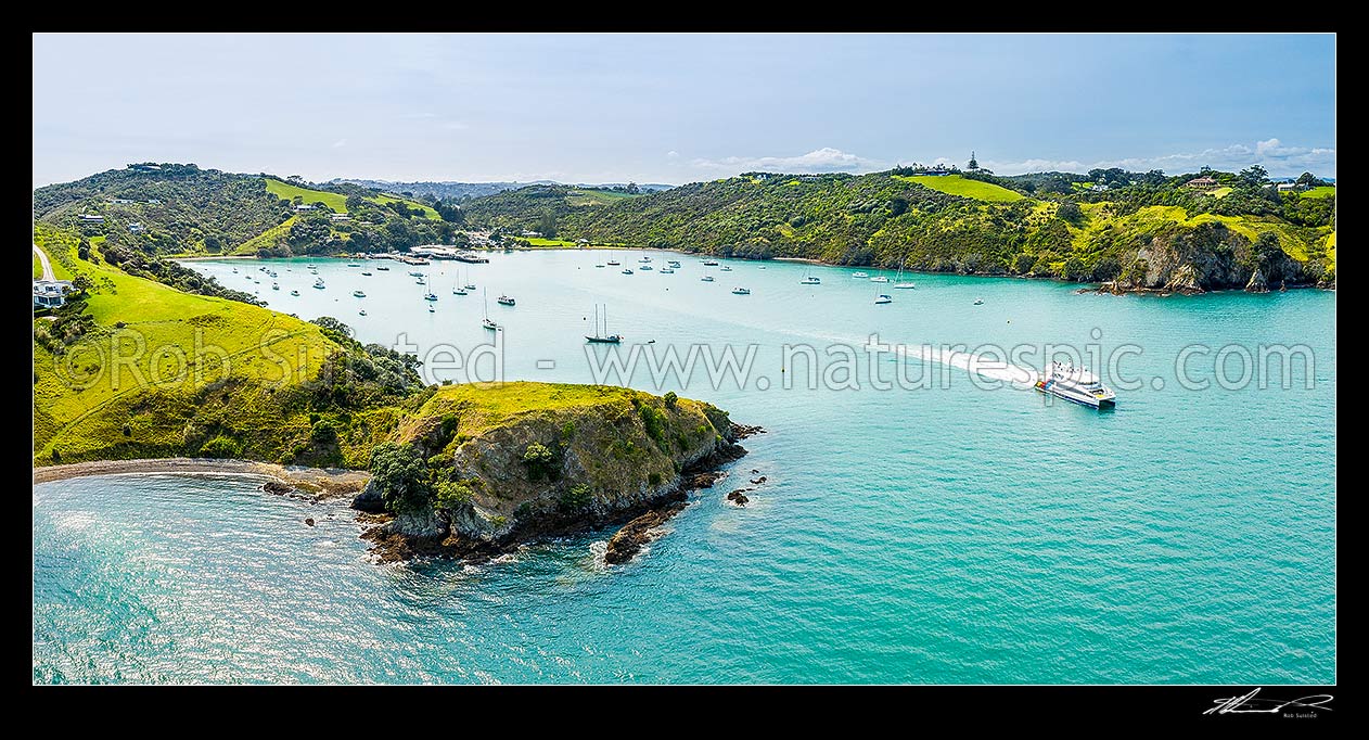 Image of Matiatia Bay ferry terminal with departing passenger ferry leaving for Auckland City. Aerial panorama, Waiheke Island, Auckland City District, Auckland Region, New Zealand (NZ) stock photo image