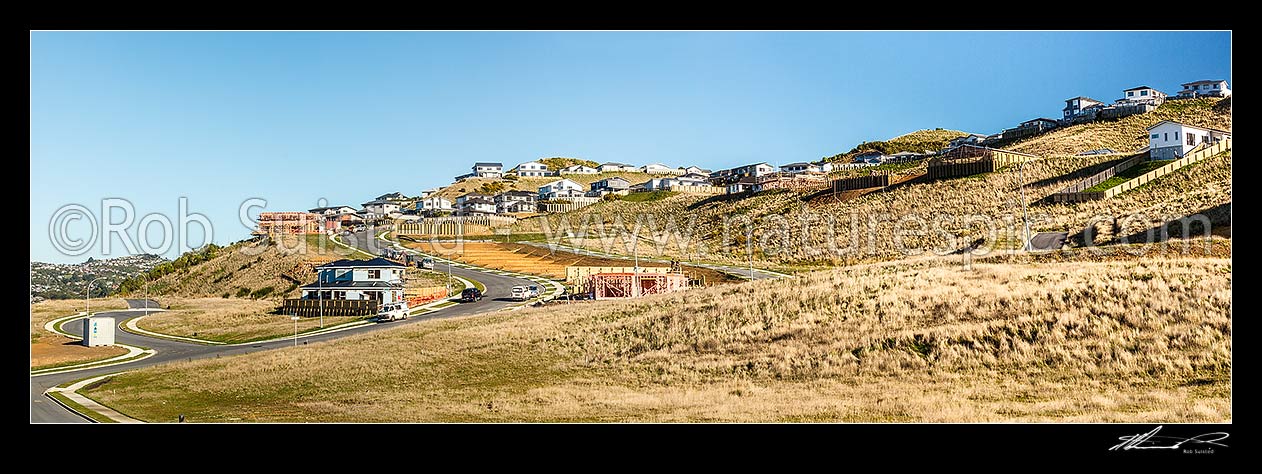 Image of New houses being built in a new suburb. Earthworks and new sections being developed with tradesmen and builders vehicles. New homes above. Panorama, Wellington City District, Wellington Region, New Zealand (NZ) stock photo image