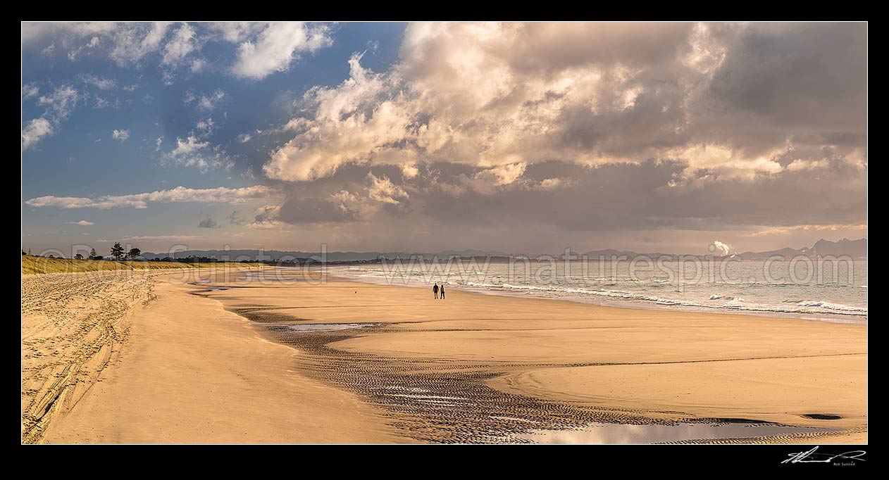 Image of Ruakaka Beach panorama, with people walking in evening light. Looking towards Whangarei, Ruakaka, Whangarei District, Northland Region, New Zealand (NZ) stock photo image