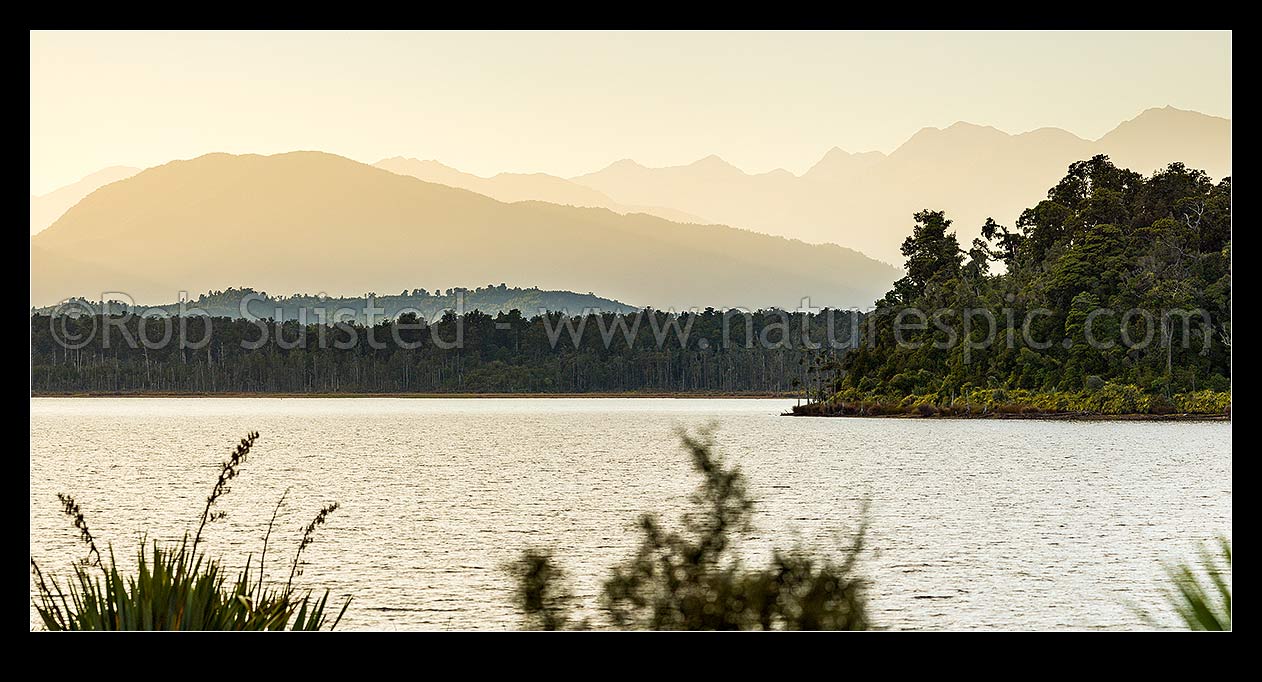 Image of Lake Mahinapua Scenic Reserve panorama at dawn, looking past Hobart Point and Picnic Bay to Mt Graham (829m) left and Southern Alps Main Divide in distance, Hokitika, Westland District, West Coast Region, New Zealand (NZ) stock photo image