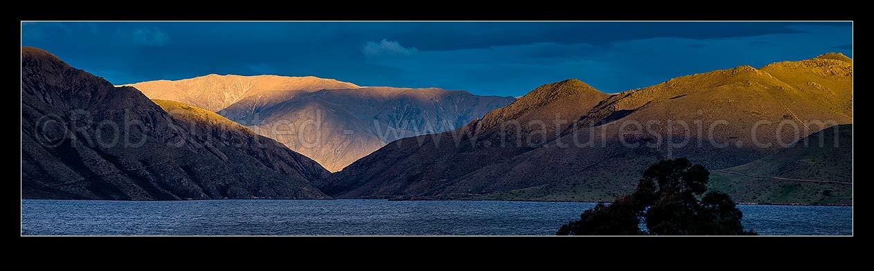 Image of Lake Benmore last light. Looking across western Lake Benmore through the narrows to Sugar Loaf (1044m) and range above. Panorama, Omarama, Waitaki District, Canterbury Region, New Zealand (NZ) stock photo image