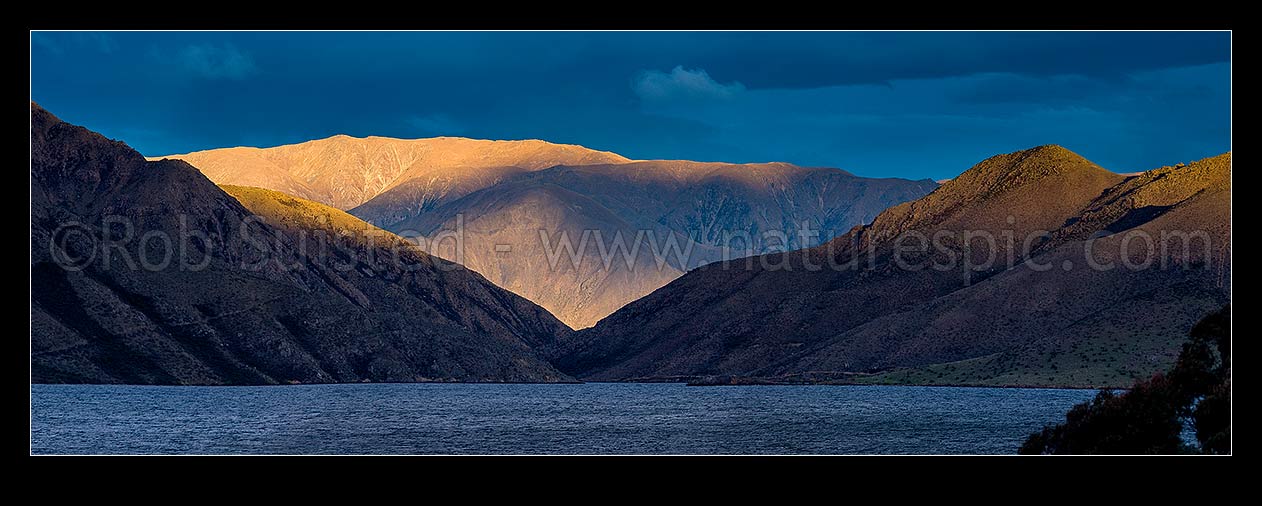 Image of Lake Benmore last light. Looking across western Lake Benmore through the narrows to Sugar Loaf (1044m) and range above. Panorama, Omarama, Waitaki District, Canterbury Region, New Zealand (NZ) stock photo image