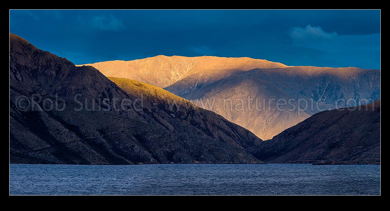 Image of Lake Benmore last light. Looking across western Lake Benmore through the narrows to Sugar Loaf (1044m) and range above. Panorama, Omarama, Waitaki District, Canterbury Region, New Zealand (NZ) stock photo image