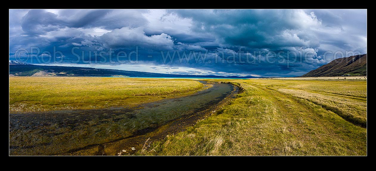 Image of Lake Pukaki's turquoise blue waters under a heavy brooding sky. Lake Pukaki lake shore and edge in the Tasman Valley where a spring fed creek passes. Panorama, Lake Pukaki, MacKenzie District, Canterbury Region, New Zealand (NZ) stock photo image