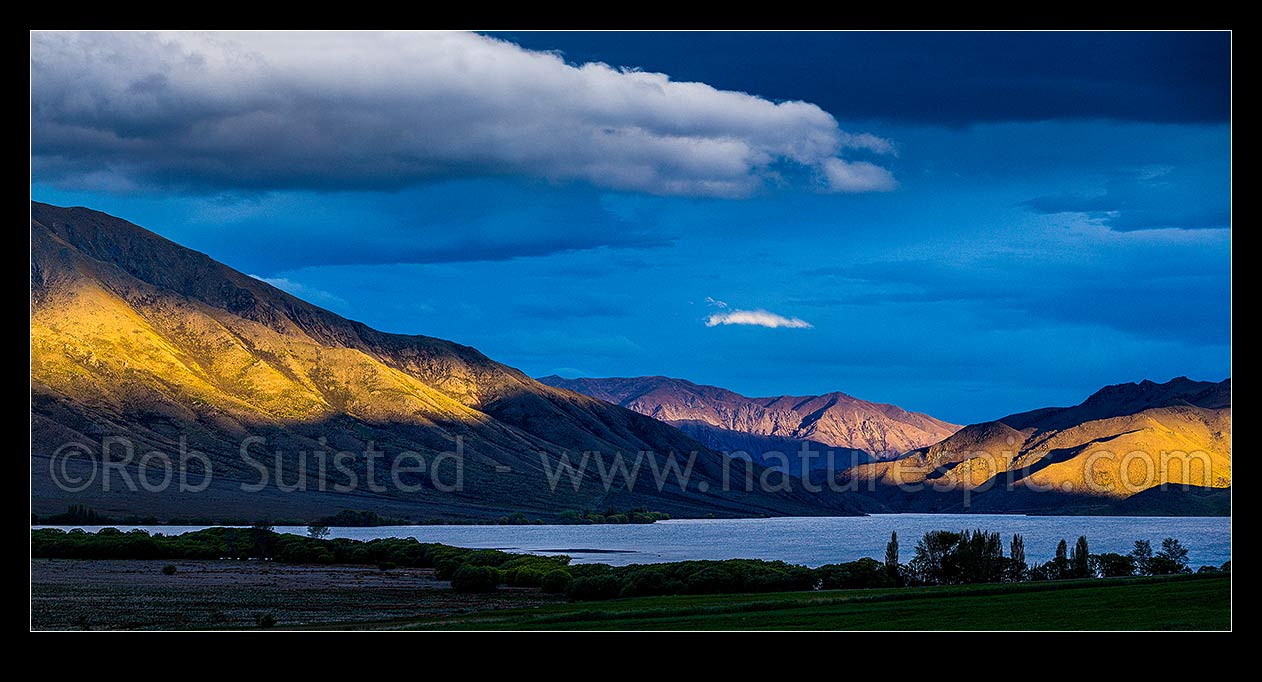 Image of Lake Benmore and surrounding high country hills in evening light. Moody panorama, Otematata, MacKenzie District, Canterbury Region, New Zealand (NZ) stock photo image