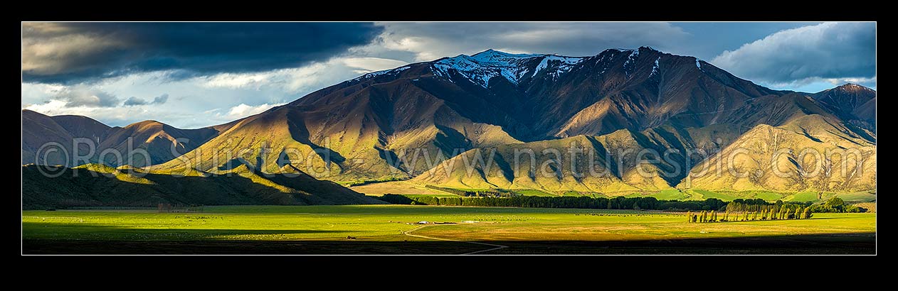 Image of Moody farmland and high country of the Benmore Range and Totara Peak (1822m above). Including dairy farmland and pivot irrigator. Panorama, Omarama, Waitaki District, Canterbury Region, New Zealand (NZ) stock photo image