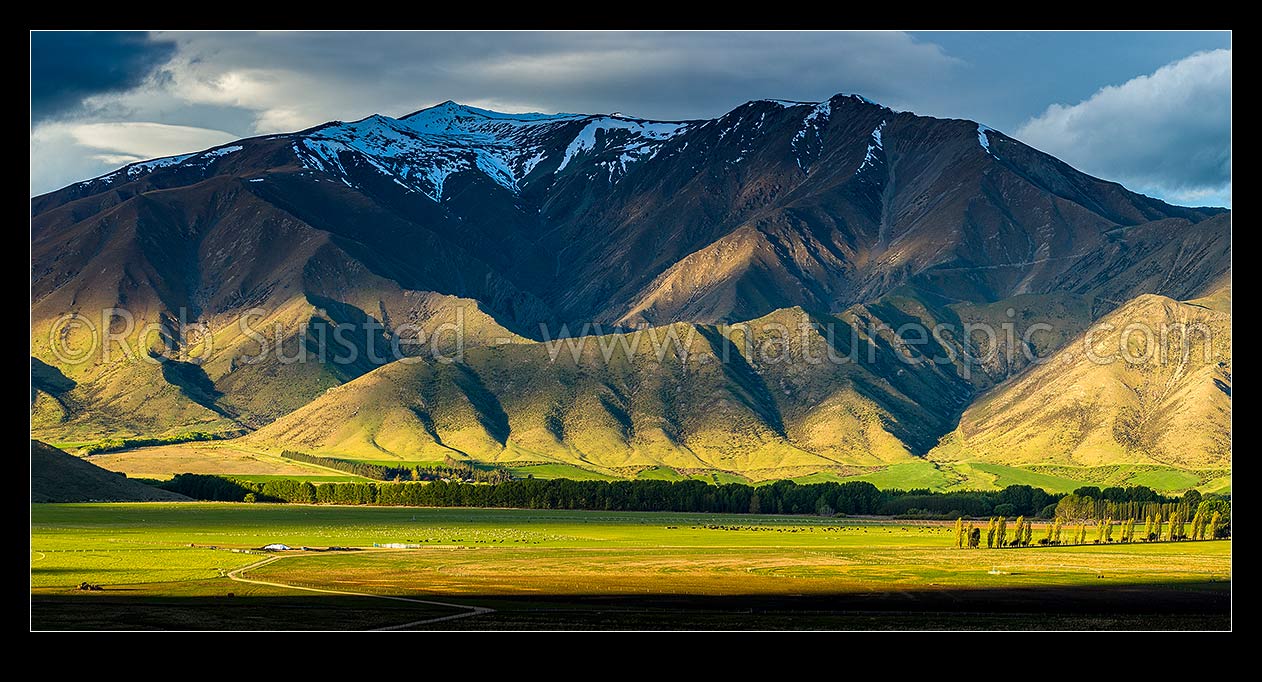 Image of Moody farmland and high country of the Benmore Range and Totara Peak (1822m above). Including dairy farmland and pivot irrigator. Panorama, Omarama, MacKenzie District, Canterbury Region, New Zealand (NZ) stock photo image