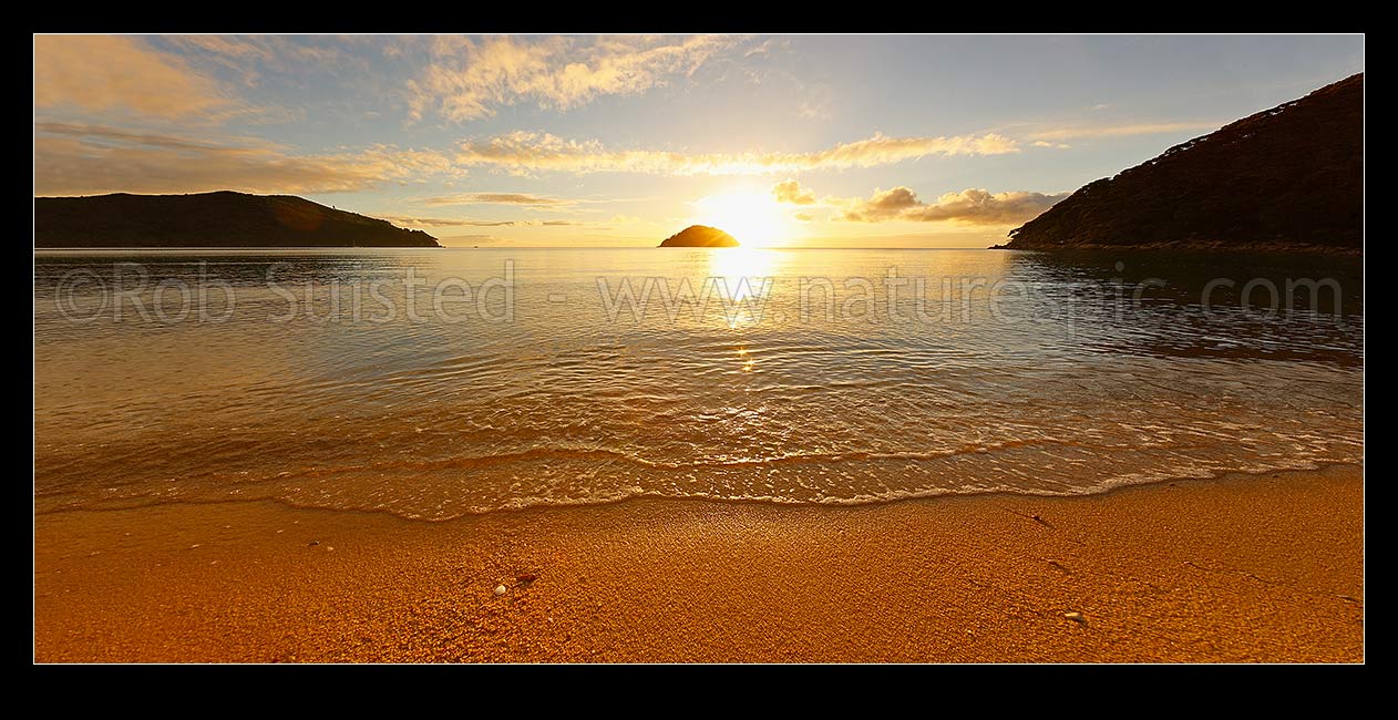 Image of Onetahuti Bay beach sunrise, with sun rising behind Tonga Island, Tonga Roadstead on a beautiful calm summer morning. Golden sand beach, Abel Tasman National Park, Tasman District, Tasman Region, New Zealand (NZ) stock photo image