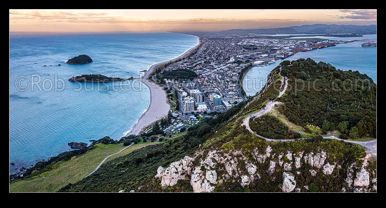 Image of Mt Maunganui summit Mauao at the Tauranga Harbour Entrance. 231m high lava dome. Mt Maunganui Beach left, Tauranga Harbour right. Aerial panorama at dusk, Mount Maunganui, Tauranga District, Bay of Plenty Region, New Zealand (NZ) stock photo image